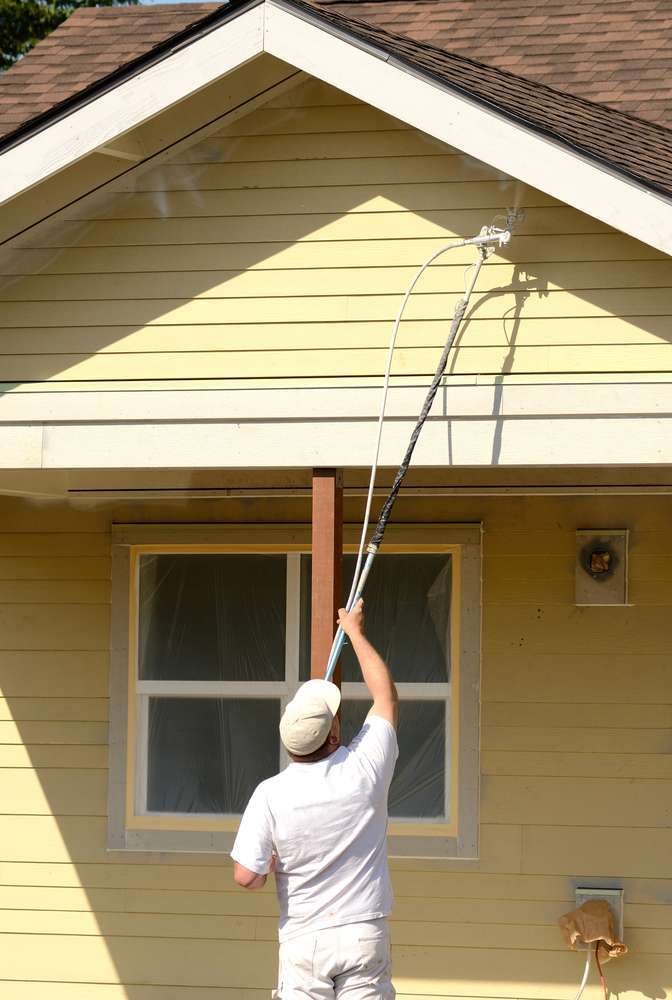 Painter Spraying soffit of house Exterior Painting Services man spraying the soffit of a home
